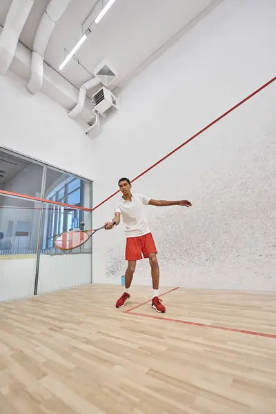 Joven deportista afroamericano jugando squash dentro de la cancha, desafío y motivación - foto de stock