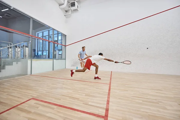 Desportistas multiculturais dinâmicos jogando squash juntos dentro da corte, desafio e motivação — Fotografia de Stock