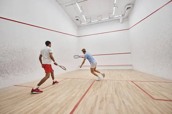 Atletas inter-raciais dinâmicos jogando squash juntos dentro do tribunal, desafio e motivação — Fotografia de Stock