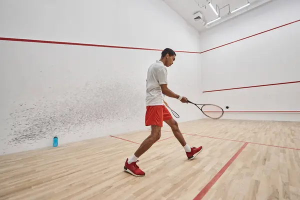Sportif afro-américain dynamique jouant au squash à l'intérieur du court, défi et motivation — Photo de stock