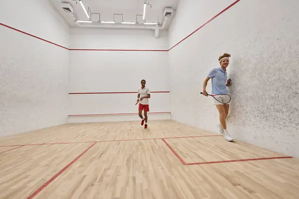 Dynamic interracial players playing squash together inside of court, challenge and motivation — Stock Photo