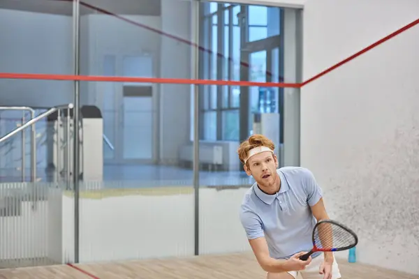 Енергійний рудий спортсмен тримає ракетку, граючи в сквош всередині двору, спортивний виклик — стокове фото
