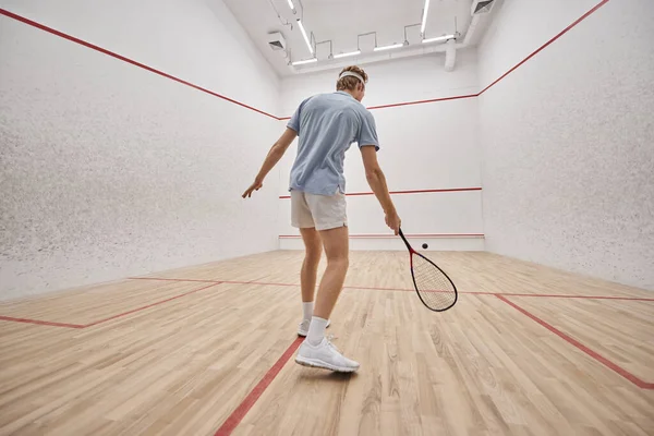 Atlético ruiva desportista segurando raquete e jogar squash dentro do tribunal, tiro movimento — Fotografia de Stock