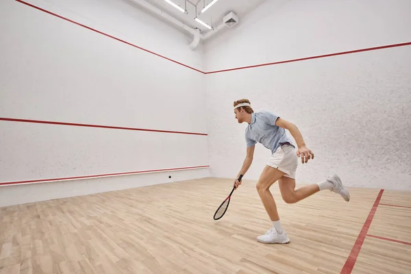 Atlético e ruiva desportista com raquete jogar squash dentro da corte, tiro movimento — Fotografia de Stock