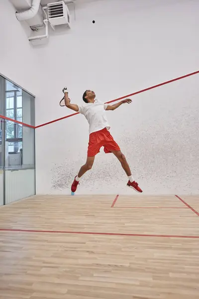 Motion shot, joueur afro-américain énergique tenant une raquette tout en sautant et en jouant au squash — Photo de stock