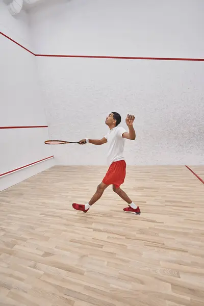 Motion shot, enérgico deportista afroamericano con raqueta jugando squash en la corte, competición — Stock Photo