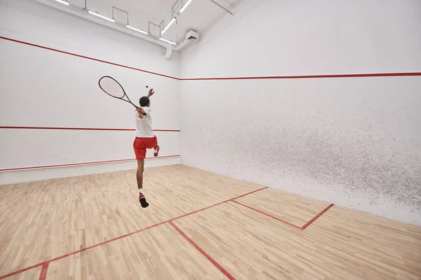 Young and athletic african american player with racquet jumping and playing squash in court — Stock Photo