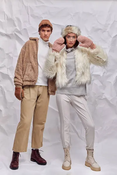 Full length of fashionably dressed interracial couple on white crumpled backdrop, winter style — Stock Photo