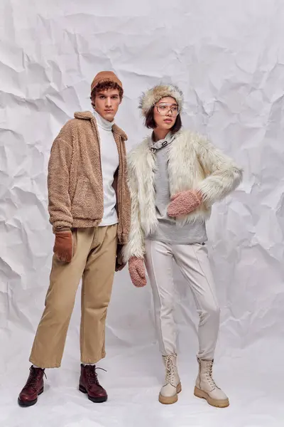 Full length of interracial couple in cozy winter attire on white textured backdrop, winter fashion — Stock Photo