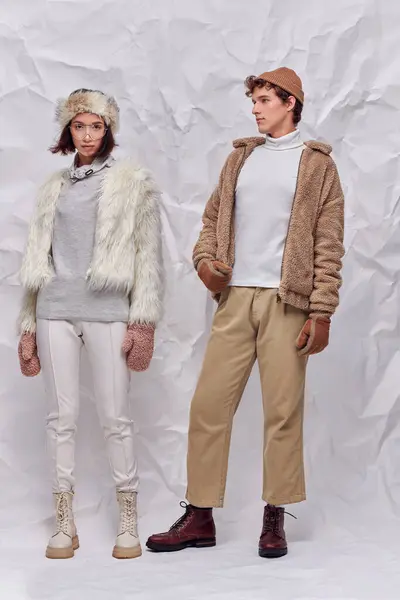 Winter fashion campaign, young interracial couple in trendy outerwear on white crumpled backdrop — Stock Photo