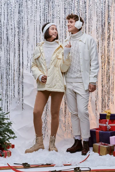 Stylish interracial couple smiling near christmas tree and presents on  backdrop with silver tinsel — Stock Photo