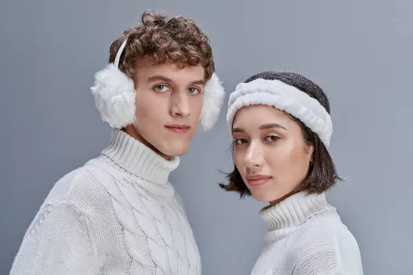 Fashion lookbook concept, portrait of interracial couple in winter outfit looking at camera on grey — Stock Photo