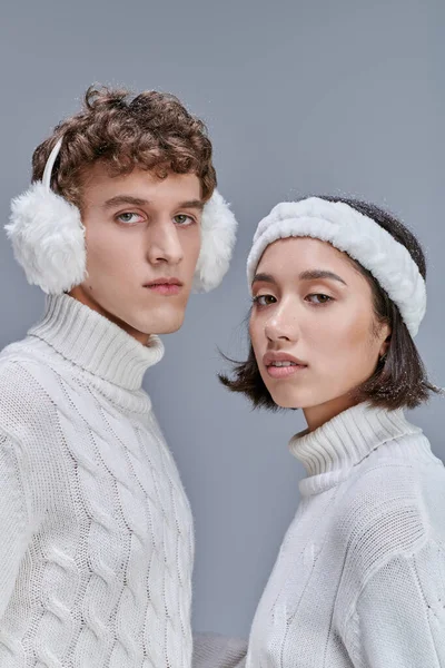 Winter fashion concept, portrait of multiethnic couple in warm outfit looking at camera on grey — Stock Photo