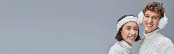 Coppia interrazziale in abito caldo sorridente fotocamera gat su sfondo grigio, stile inverno urbano, banner — Foto stock
