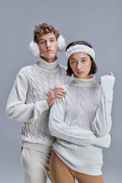 Moda vestito coppia interrazziale guardando fotocamera su sfondo grigio, concetto di moda invernale — Foto stock