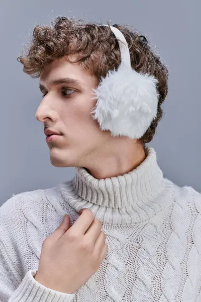 Profilo ritratto di uomo di tendenza in caldo paraorecchie e maglione bianco lavorato a maglia su grigio, moda invernale — Foto stock