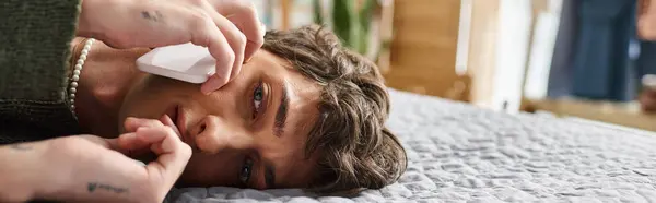 Young and curly transgender person in casual attire talking on smartphone in bedroom, banner — Stock Photo