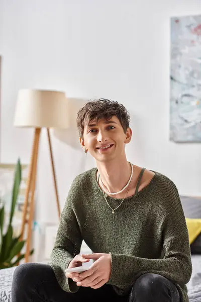 Happy transgender person in casual attire looking at camera and sitting in modern apartment — Stock Photo