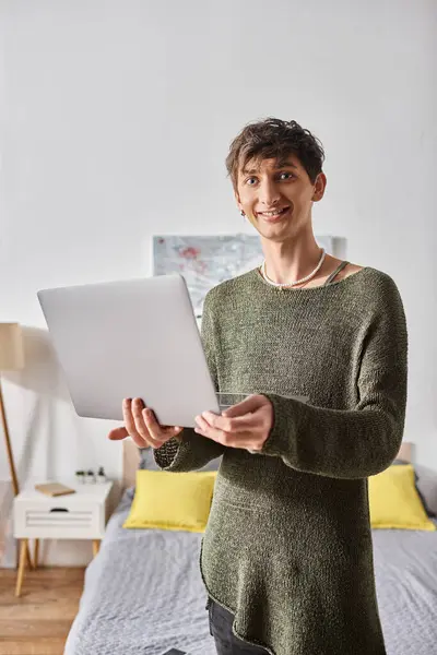 Transgender blogger with curly hair using laptop while standing in modern apartment, influencer — Stock Photo