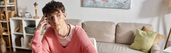 Задумчивый трансгендерный фрилансер в розовом свитере и очках, смотрящий в сторону дома, баннер — стоковое фото