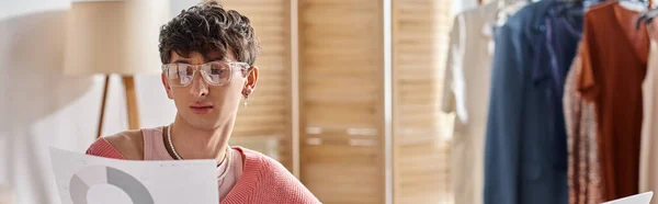 Freelance androgyne bouclée en pull rose et lunettes travaillant à distance, bannière paperasse — Photo de stock