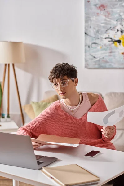 Curly androgynous freelancer in pink sweater and eyeglasses working remotely near devices on desk — Stock Photo