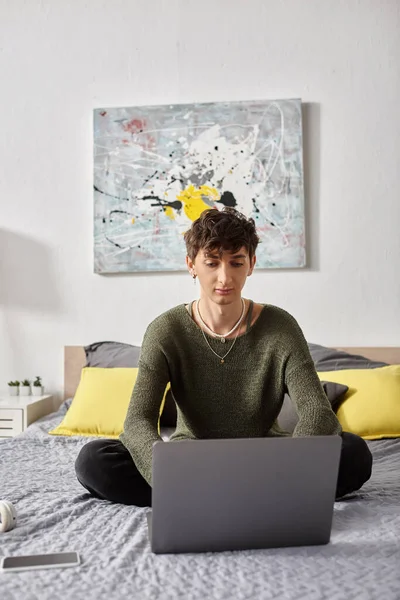 Lockige Transgender-Bloggerin mit Laptop und im Bett in einer modernen Wohnung, Social Media — Stockfoto