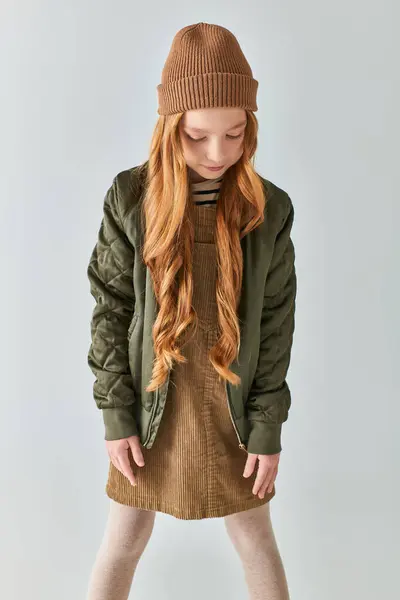 Carino preteen ragazza con i capelli lunghi in posa in abito invernale e cappello a maglia su sfondo grigio — Foto stock
