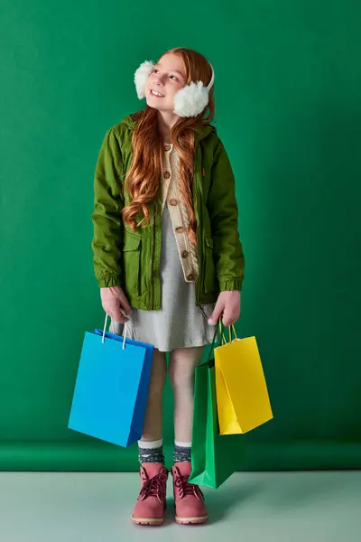 Черный пятница и праздничный сезон, мечтательная девушка в зимнем наряде и наушники с сумками для покупок — стоковое фото