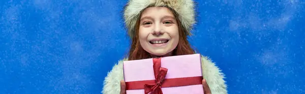 Winterurlaubsbanner, fröhliches Mädchen in Kunstpelzjacke und Hut mit eingewickelter Geschenkbox auf Türkis — Stockfoto
