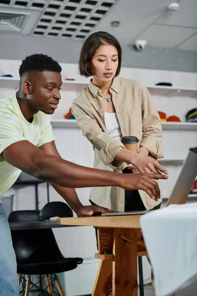 Designer multietnici che puntano al laptop mentre lavorano a un nuovo progetto nel laboratorio di stampa tessile — Foto stock
