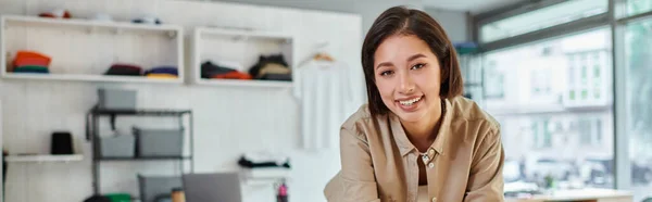 Junge erfolgreiche asiatische Modedesignerin lächelt in moderner Druckerei in die Kamera, horizontales Banner — Stockfoto