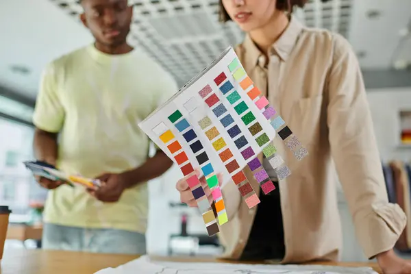 Vista cortada da mulher segurando paleta de cores perto de designer americano africano no estúdio de impressão — Fotografia de Stock