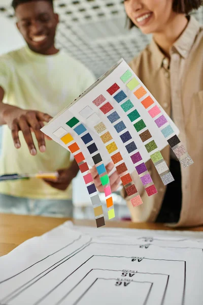 Розмиті міжрасові дизайнери моди тримають кольорову палітру під час роботи в друкованій студії, командній роботі — стокове фото