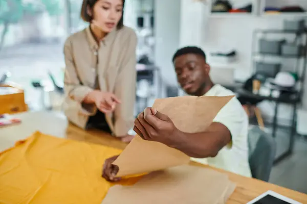 Young interracial entrepreneurs working with sewing patterns in print studio, creative manufacturing — Stock Photo