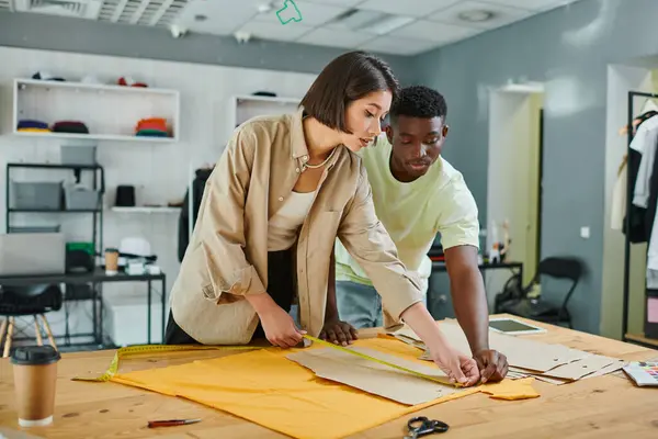Young interracial fashion designers measuring sewing patterns in print studio, creative teamwork — Stock Photo