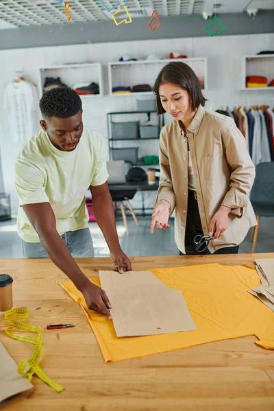 Designer di abiti multiculturali creativi che lavorano con modelli di cucito in un moderno studio di stampa — Foto stock