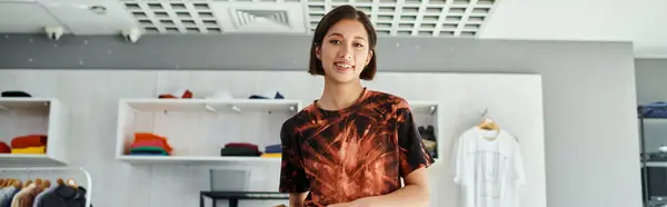 Joven éxito asiático diseñador de moda sonriendo a la cámara en moderno estudio de impresión, bandera horizontal - foto de stock