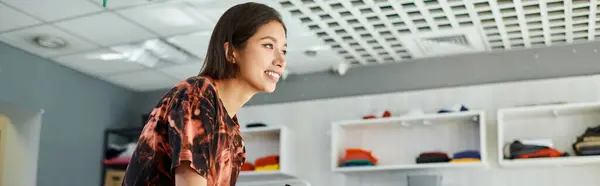 Молода і весела азіатська бізнес-леді посміхається і дивиться в друковану студію, горизонтальний банер — стокове фото