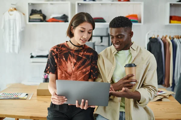 Ambitious interracial designers looking at laptop while discussing startup in print studio, teamwork — Stock Photo