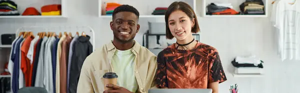 Designers inter-raciais de sucesso com laptop e copo de papel sorrindo para a câmera no estúdio de impressão, banner — Fotografia de Stock