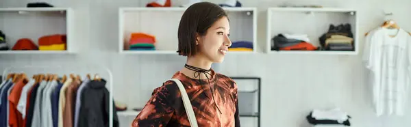 Joyeux et à la mode asiatique créateur de mode souriant dans le studio d'impression textile, bannière horizontale — Photo de stock