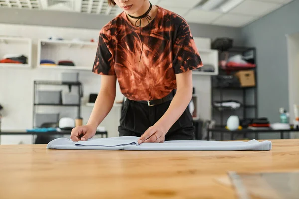 Обрізаний вид стильної азіатки, розкладний одяг на столі в друкованій майстерні, індустрія моди — стокове фото
