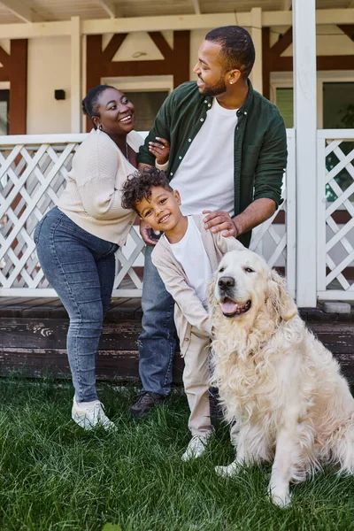 Tiempo de la familia, padres afroamericanos felices e hijo jugando con el perro en el patio trasero de su casa — Stock Photo
