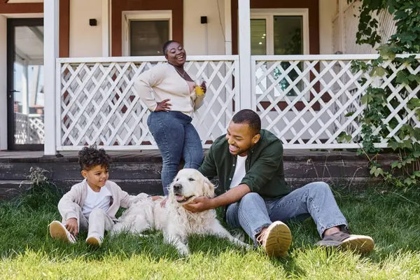 Tempo de família, filho pai americano africano feliz brincando com cão perto de mulher no quintal da casa — Fotografia de Stock