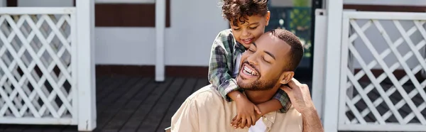 Positive african american kid hugging father while having bbq on backyard of house, banner — Stock Photo