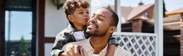 Bonito afro-americano menino abraçando animado pai no aparelho no quintal da casa, bandeira — Fotografia de Stock