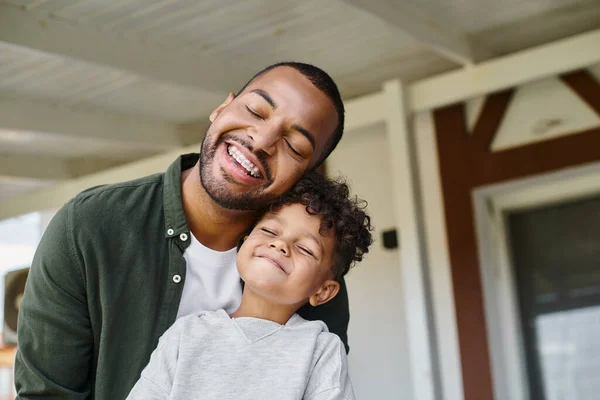 Joyeux garçon afro-américain et père joyeux souriant avec les yeux fermés tout en ayant du bon temps — Photo de stock