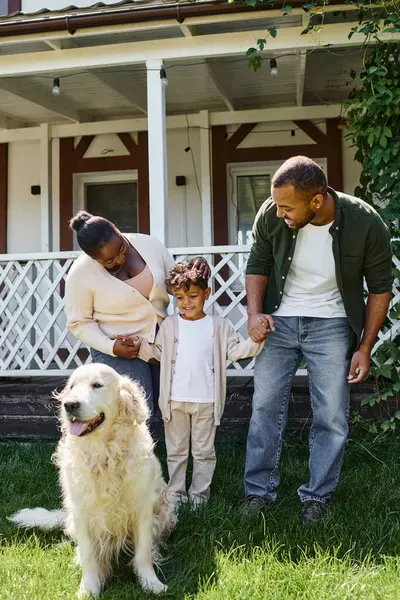 Moments heureux, parents afro-américains joyeux et fils souriant chien proche de la famille sur la cour de la maison — Photo de stock