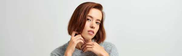 Attractive woman with brunette and short hair sitting in winter sweater grey backdrop, banner — Stock Photo